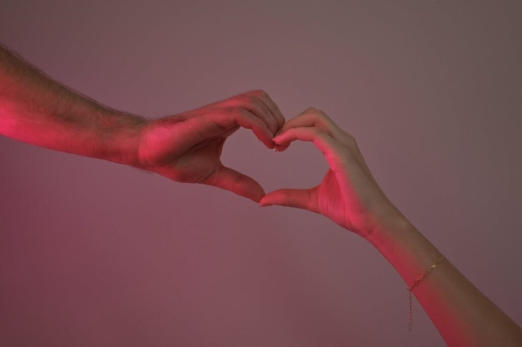 zipwp-image-20212667 Two hands making a heart shape with pink light