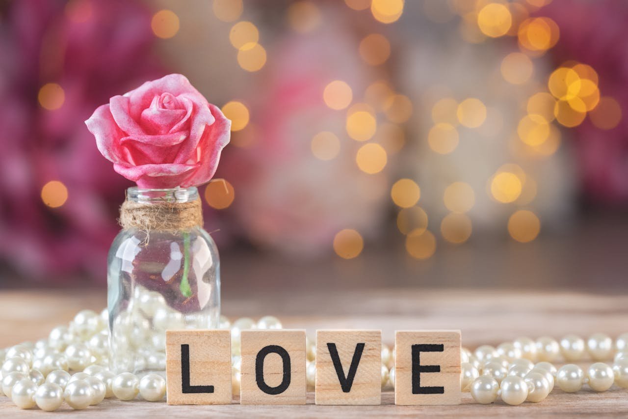 A pink rose and a love word on a wooden block